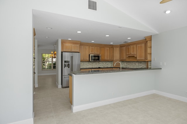 kitchen with kitchen peninsula, appliances with stainless steel finishes, backsplash, light tile patterned floors, and dark stone countertops