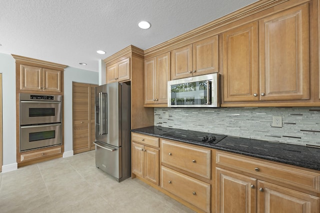 kitchen featuring dark stone countertops, a textured ceiling, decorative backsplash, light tile patterned floors, and appliances with stainless steel finishes