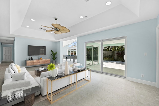 living room featuring ceiling fan, light tile patterned floors, and a tray ceiling