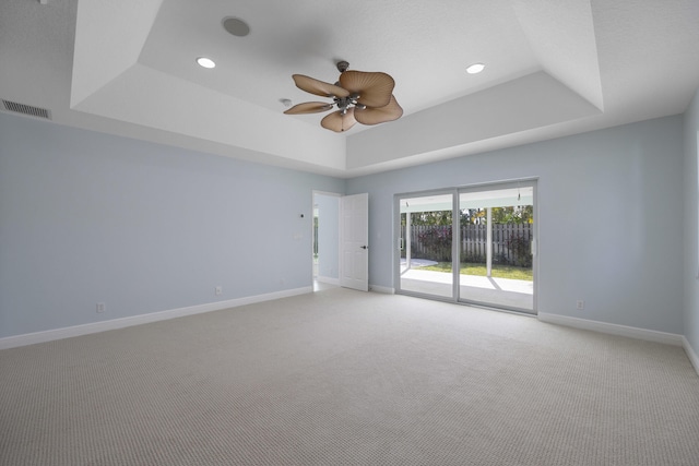 carpeted spare room featuring a raised ceiling and ceiling fan