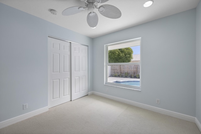 unfurnished bedroom featuring ceiling fan, a closet, and light carpet