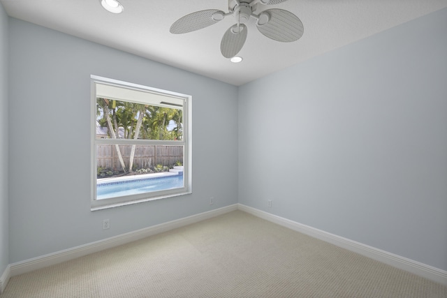 carpeted spare room featuring ceiling fan