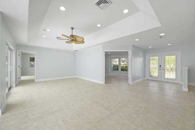 empty room featuring french doors, light tile patterned floors, a raised ceiling, and ceiling fan