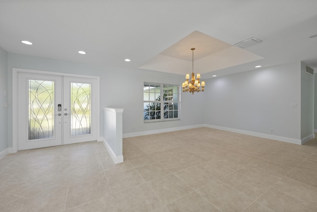 tiled entrance foyer with a raised ceiling, french doors, and a notable chandelier