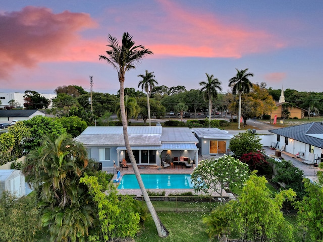 back house at dusk featuring a patio area