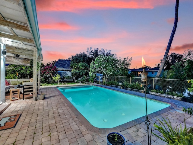 pool at dusk featuring an outdoor hangout area and a patio area