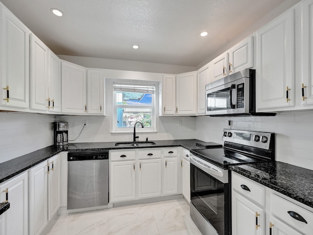 kitchen featuring white cabinetry, sink, dark stone counters, and appliances with stainless steel finishes