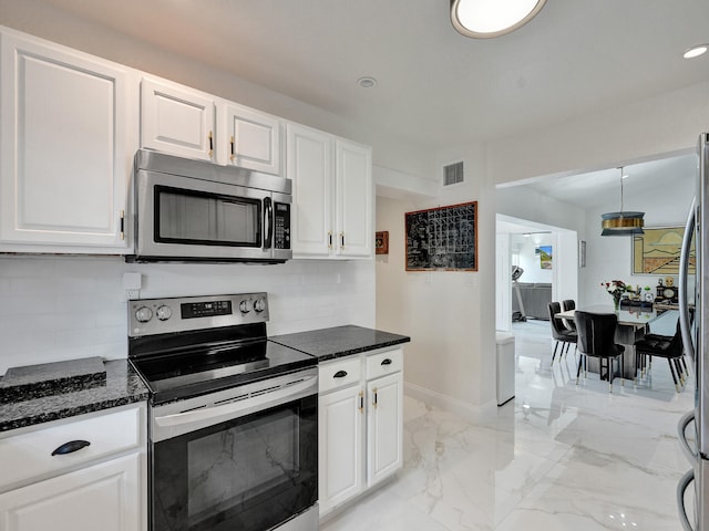 kitchen featuring white cabinets, decorative light fixtures, backsplash, and stainless steel appliances