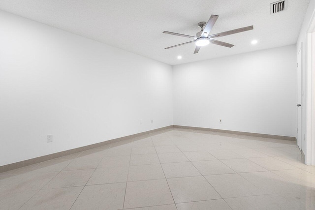 spare room with a textured ceiling, ceiling fan, and light tile patterned flooring