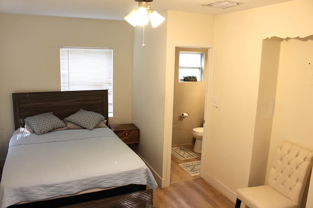 bedroom with ceiling fan, wood-type flooring, and ensuite bath