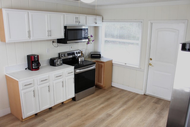 kitchen with light wood-type flooring, appliances with stainless steel finishes, and white cabinetry