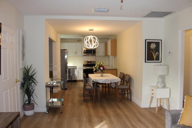 dining space featuring a textured ceiling, dark hardwood / wood-style flooring, and a notable chandelier