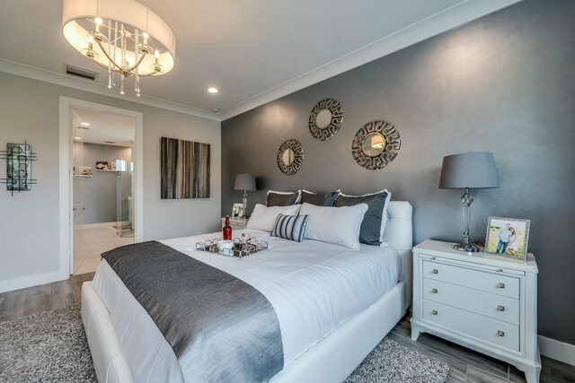 bedroom featuring ensuite bathroom, wood-type flooring, ornamental molding, and an inviting chandelier