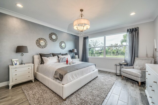 bedroom with crown molding, light hardwood / wood-style flooring, and a notable chandelier