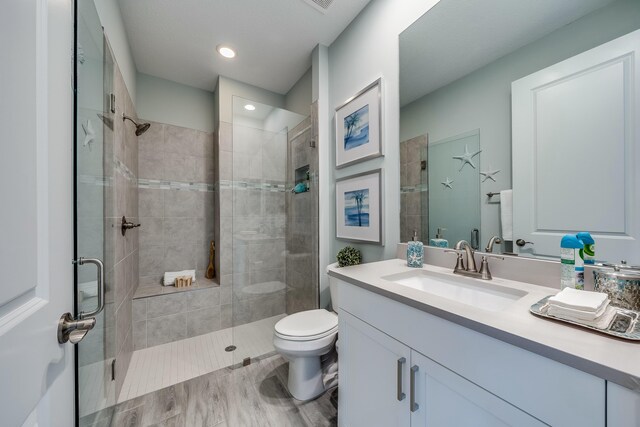 bathroom with hardwood / wood-style floors, vanity, toilet, and walk in shower