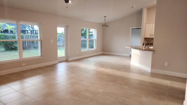206 Riomar Dr, Port Saint Lucie, FL 34952 - interior space featuring a sink, light tile patterned flooring, vaulted ceiling, baseboards, and ceiling fan with notable chandelier