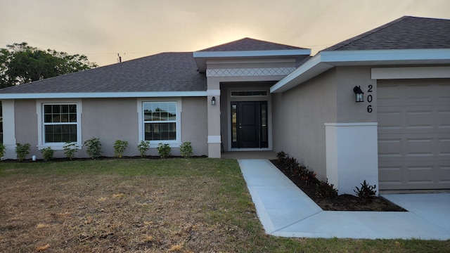206 Riomar Dr, Port Saint Lucie, FL 34952 - property entrance featuring an attached garage, a lawn, roof with shingles, and stucco siding