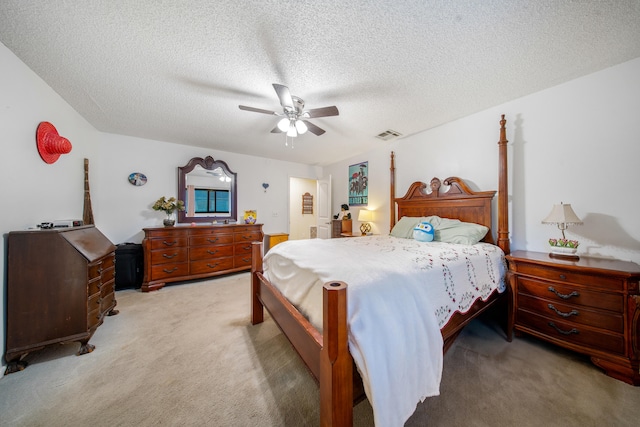 bedroom with ceiling fan, light colored carpet, and a textured ceiling