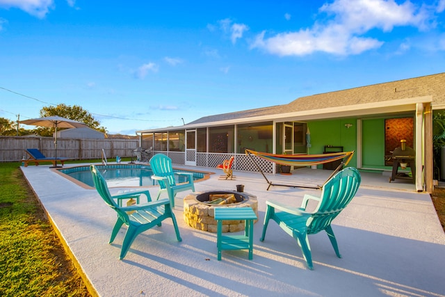 view of pool featuring a sunroom, an outdoor fire pit, and a patio