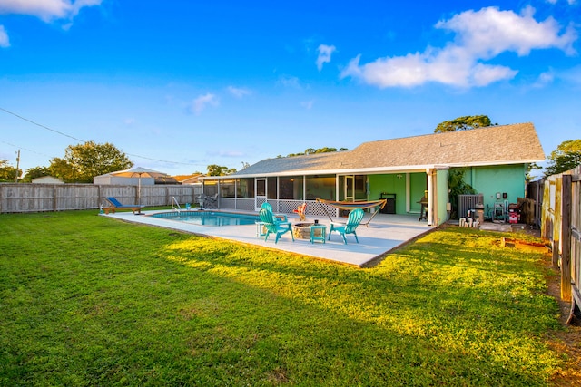 rear view of house with a fenced in pool, a patio, a sunroom, and a yard