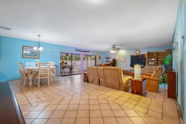 dining room featuring ceiling fan with notable chandelier, light tile patterned floors, and a textured ceiling