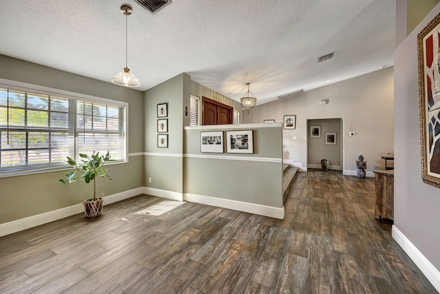 kitchen featuring a textured ceiling, hardwood / wood-style floors, hanging light fixtures, and lofted ceiling