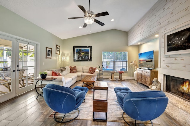 living room with plenty of natural light, wood-type flooring, lofted ceiling, and french doors