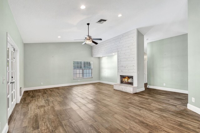 living room with ceiling fan, a large fireplace, vaulted ceiling, and light hardwood / wood-style flooring