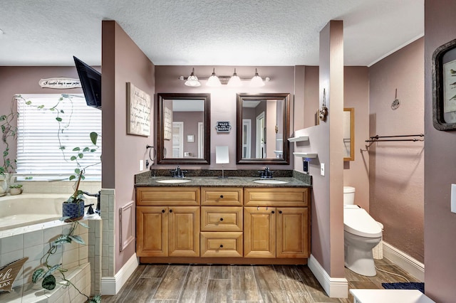 bathroom featuring a washtub, wood-type flooring, a textured ceiling, toilet, and vanity