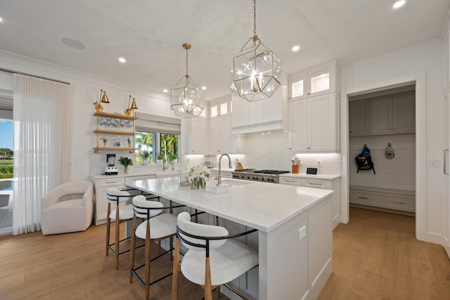 kitchen with white cabinetry, sink, a center island with sink, and backsplash