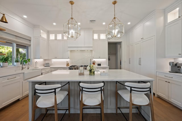 kitchen with white cabinetry, hanging light fixtures, and a kitchen island