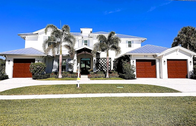 view of front facade with driveway, a front lawn, a standing seam roof, an attached garage, and metal roof