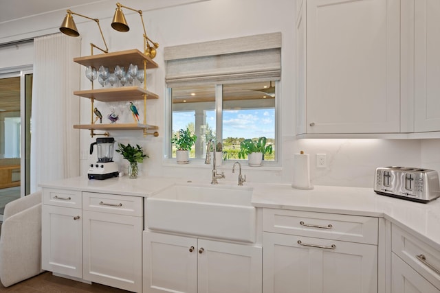 kitchen featuring white cabinetry, sink, decorative backsplash, and light stone countertops