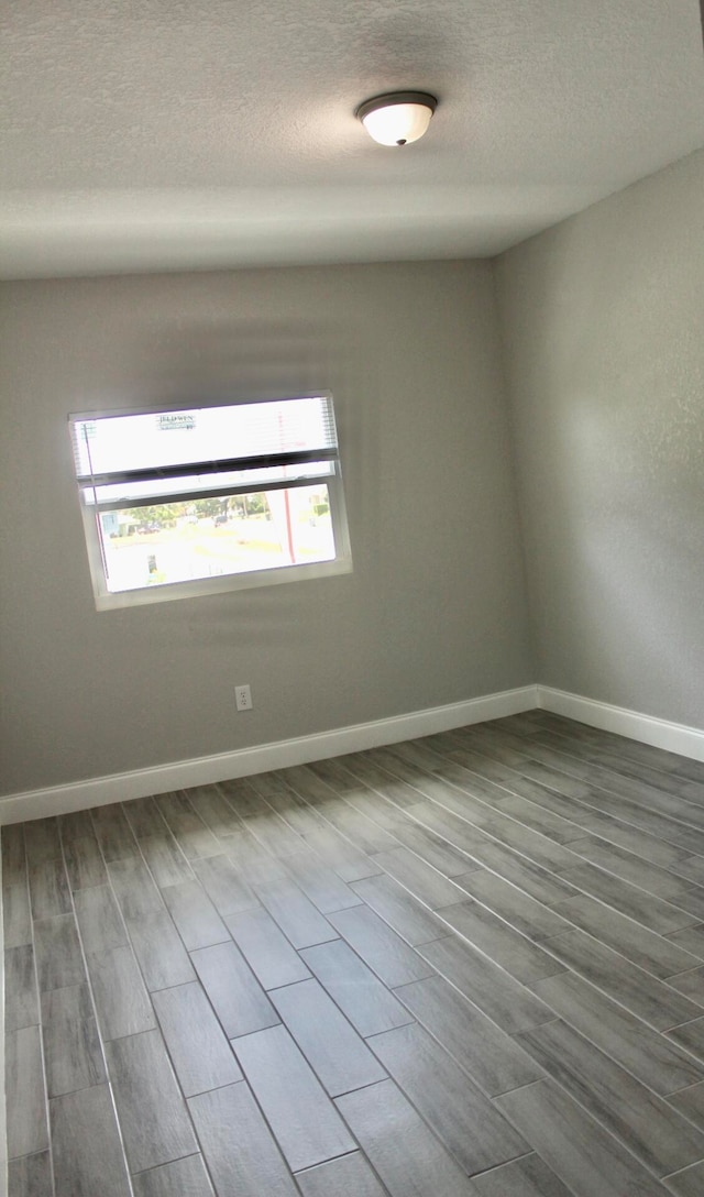 unfurnished room with wood-type flooring and a textured ceiling