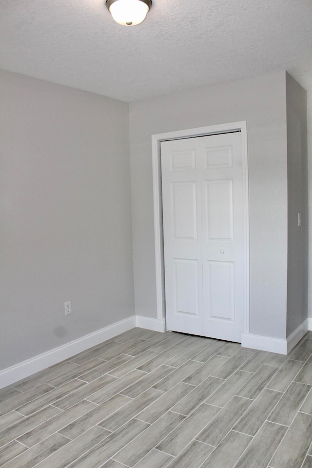 spare room with a textured ceiling and light hardwood / wood-style flooring