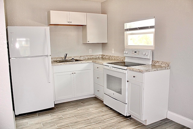 kitchen with white cabinetry, sink, white appliances, and light hardwood / wood-style flooring