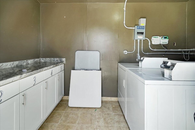 laundry room featuring washer and clothes dryer, light tile patterned floors, and cabinets