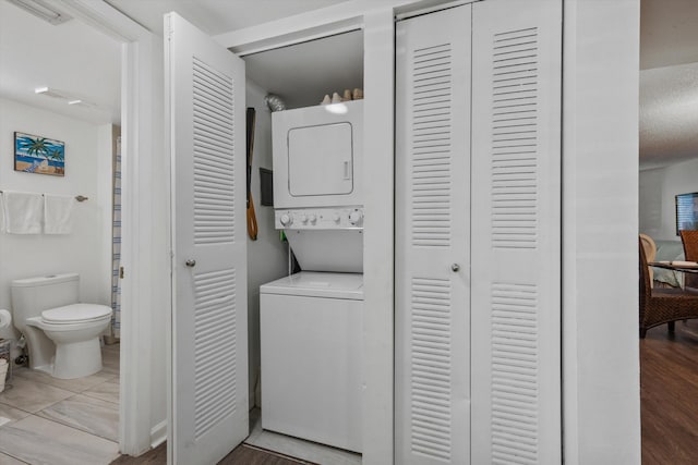 laundry area featuring hardwood / wood-style floors and stacked washing maching and dryer