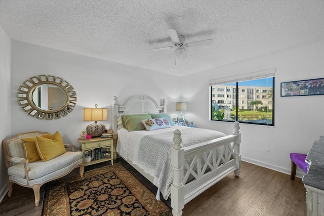 bedroom with ceiling fan, dark wood-type flooring, and a textured ceiling