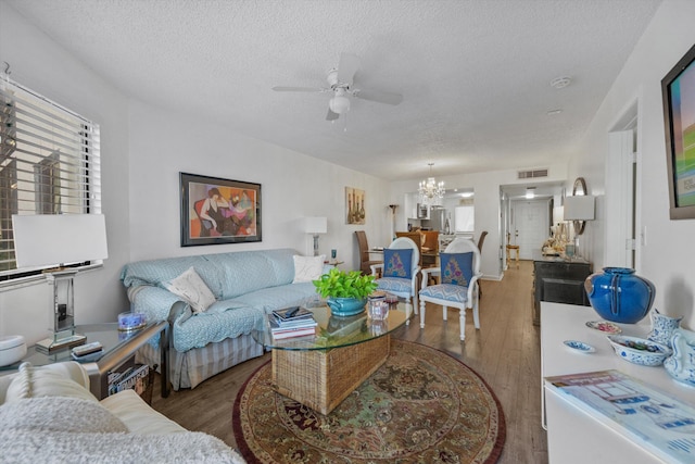 living room featuring ceiling fan with notable chandelier, a textured ceiling, and hardwood / wood-style flooring