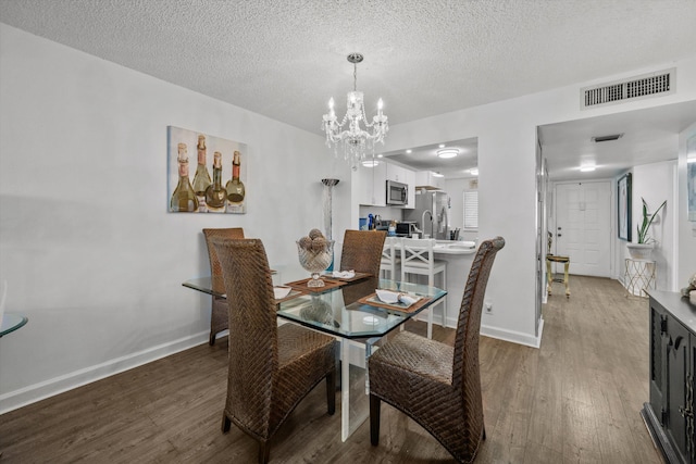 dining area with a chandelier, wood-type flooring, and a textured ceiling