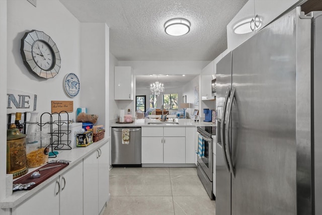 kitchen with white cabinetry, sink, hanging light fixtures, light tile patterned floors, and appliances with stainless steel finishes