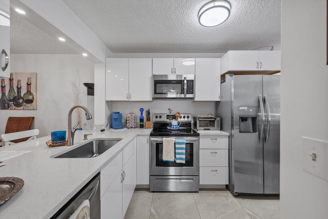 kitchen featuring white cabinetry, sink, a textured ceiling, light tile patterned flooring, and appliances with stainless steel finishes