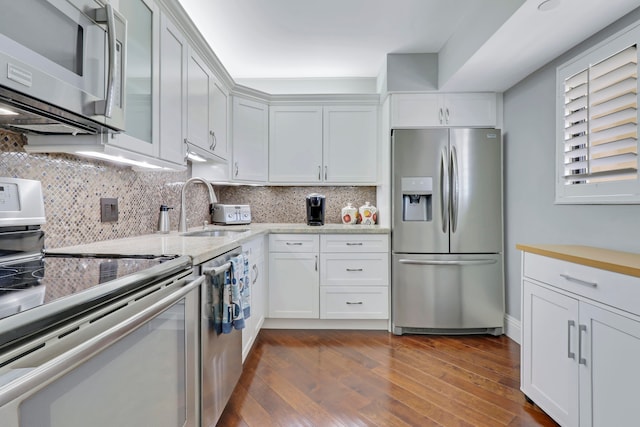 kitchen featuring dark wood-type flooring, white cabinets, sink, decorative backsplash, and stainless steel appliances