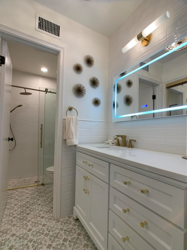 bathroom featuring walk in shower, vanity, tile walls, and toilet