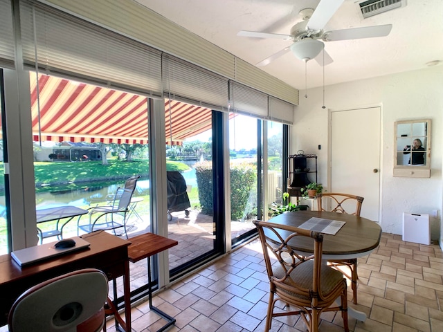 dining space with a water view and ceiling fan