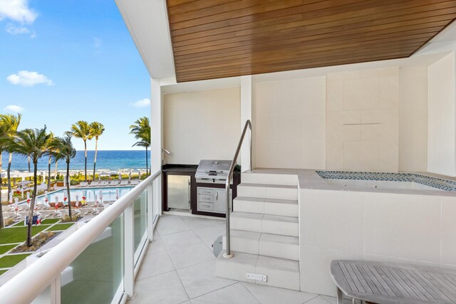 balcony with a water view, grilling area, and exterior kitchen