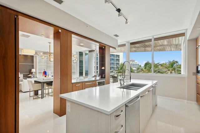 kitchen featuring track lighting, sink, an inviting chandelier, white cabinets, and an island with sink