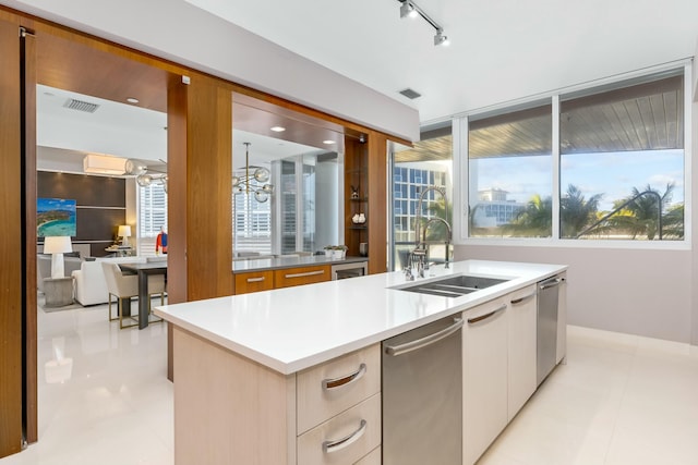 kitchen featuring an island with sink, rail lighting, sink, and plenty of natural light