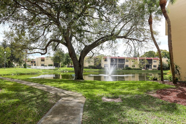 view of property's community with a lawn and a water view